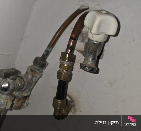 צינור ומחבר מתכת על קיר לבן